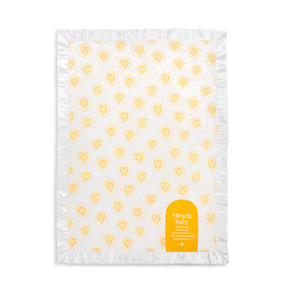 A white blanket with a white satin border and yellow hearts all over. There is a message at the bottom about a Miracle Baby.