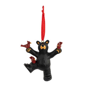 A black bear ornament hanging from a red ribbon. The bear has three red birds perched on him.