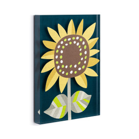 A dark blue acrylic wall art tile with an illustrated sunflower in brown, yellow and green displayed angled to the right.