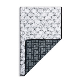 A rectangular double sided towel. One side is white with black dots and the other is black with short white lines, displayed with the black corner turned back.