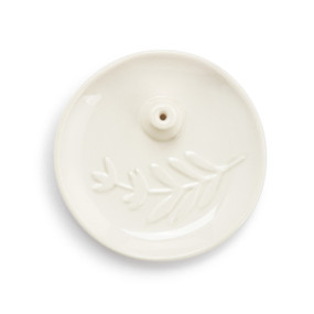 Top down view of a cream ceramic round plate with a small hole for holding incense sticks.