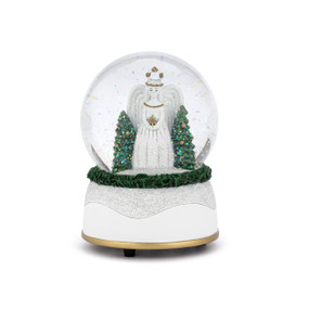 A musical snow globe with a white base and a white angel inside with two decorated trees.