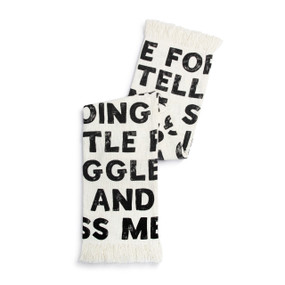 A white fringed blanket with large black bold words on it displayed folded over itself.