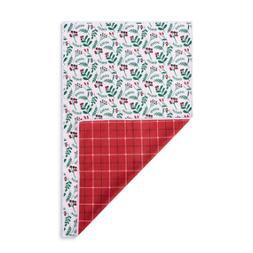 A rectangular double sided towel. One side is white with illustrated holly leaves and berries and the other is red and white plaid, displayed with the red corner turned back.