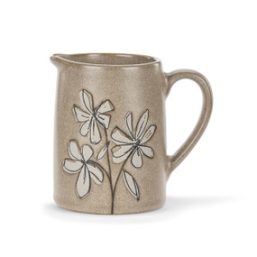 A mini brown pitcher with a handle and illustrated cream magnolia flowers on the front.