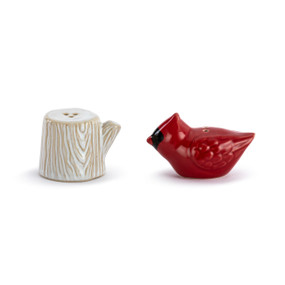 A set of ceramic salt and pepper shakers. One is cream and shaped like a tree stump and the other is a red cardinal.