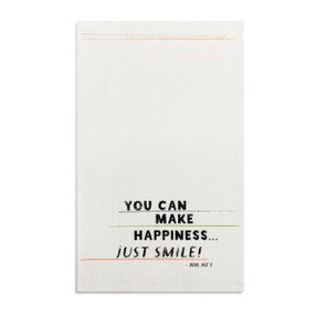 A white kitchen towel with the saying "You can make happiness...just smile" displayed laid out flat.