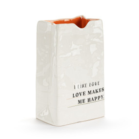 A small white ceramic vase that looks like a crinkly paper bag. The interior is orange and the saying "I like love Love makes me happy" on the front.