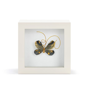 A black and gold butterfly with gold wire tentacles in a white shadow box.