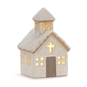 A cream church shaped ceramic light up figure with a brown door and snow on the roof, displayed lit up.