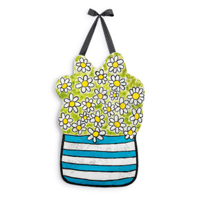 A reversible metal door hanger in the shape of a pot of flowers. The front is daisies in a blue and white pot and is hanging from a black polka dot ribbon.