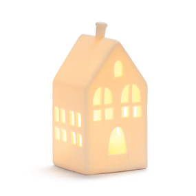 A white ceramic light up house figure with an arched doorway displayed lit.