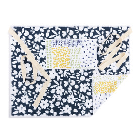 A blue and white half apron with a floral pattern on the front along with a pocket and cream ties.