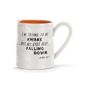 A white ceramic mug with a crinkly appearance. The interior is orange and the saying "I'm trying to be awake but my eyes keep falling down" is on the front.
