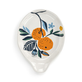 Top down view of a white ceramic spoon rest with illustrated citrus fruit and flowers in orange and blue.