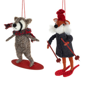 Two different felt ornaments including a racoon and a fox. One is on a snowboard and the other on snow shoes.