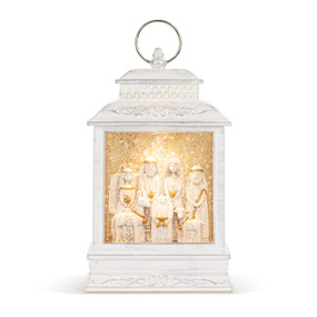 A white lit musical lantern with figures of the nativity inside.