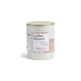 A 3.5 oz leather blossom scented candle in a round white container with a gold lid.