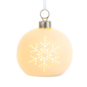 A small white ceramic ornament that lights up with a snowflake cut out on the front displayed lit.