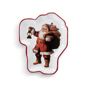 A white ceramic plate with a red rim and an illustrated image of Santa holding a bag of gifts and a lantern. The plate is shaped like Santa.