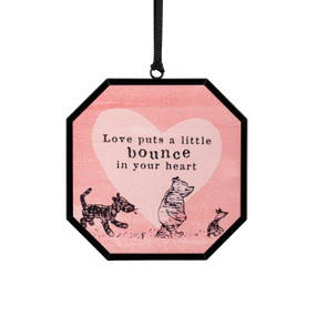 A small pink octagon shaped sun catcher with a classic illustration of Pooh and friends and the saying "Love puts a little bounce in your heart".