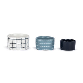 A set of three small ceramic nesting bowls in blue, navy and white plaid and dot patterns.
