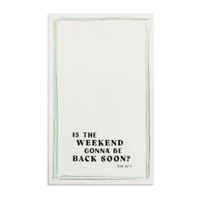 A white kitchen towel with the saying "Is the weekend gonna be back soon" displayed laid out flat.