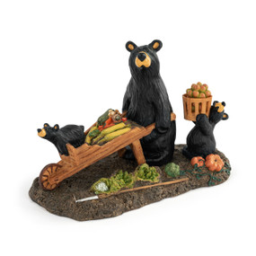 A figurine of a black bear and two black bear cubs harvesting their garden and pushing a wheelbarrow full of produce.