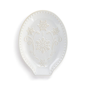 A cream ceramic spoon rest with a snowflake and swirl design.