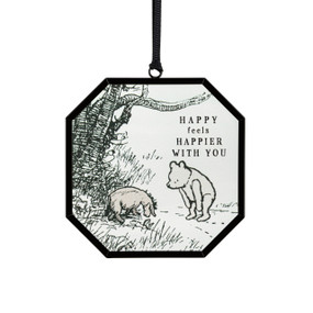 A small octagon shaped sun catcher with a classic illustration of Pooh and Eyeore and the saying "Happy feels Happier with you".