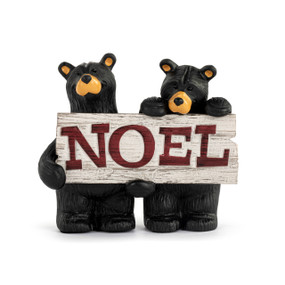 A figurine of two black bears holding a white wood sign with the word "Noel" in red.