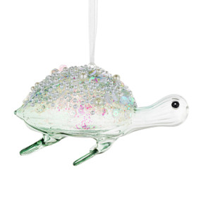 A light green glass sea turtle shaped ornament decorated with different beads on top.