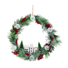 A green frosted wreath decorated with red berries, white balls and white village buildings at the bottom.
