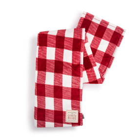 A red and white plaid blanket with a fabric patch in the corner with the saying "Tis the Season to be Comfy & Cozy".