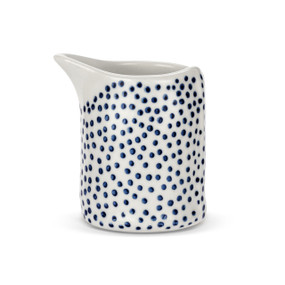 A micro sized white ceramic pitcher covered with blue dots.