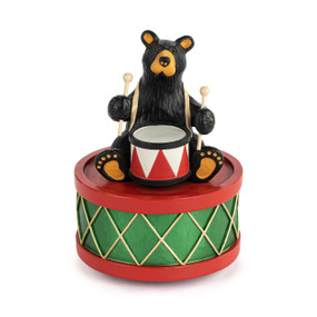 A musical black bear figurine where the base looks like a red and green drum and there is a black bear sitting on the top holding a snare drum.