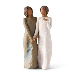 Front view: Figure of two women with darker skin tones in different colored dresses, standing arm in arm