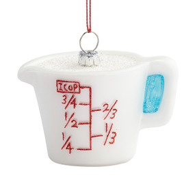 A white measuring cup ornament with the measures written in red.