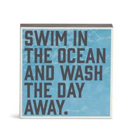 A blue wall art with the saying "Swim in the ocean and wash the day away".