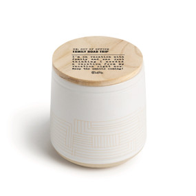 A white ceramic jar candle. The lid is wood with the saying "RE: Out of the Office family road trip" with a short write up about someone on a family vacation.