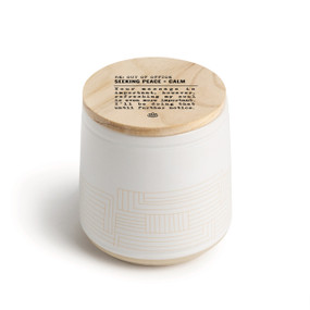 A white ceramic jar candle. The lid is wood with the saying "RE: Out of the Office seeking peace + calm" with a short write up about someone seeking calm.