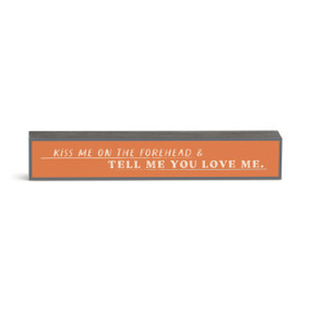 An orange rectangular wall art with the saying "Kiss me on the forehead & tell me you love me."