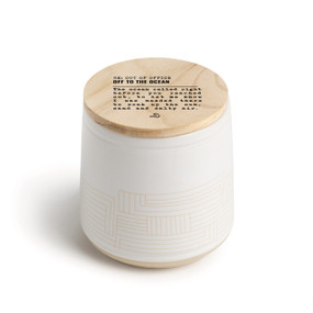 A white ceramic jar candle. The lid is wood with the saying "RE: Out of the Office Off to the ocean" with a short write up about someone on an ocean vacation.
