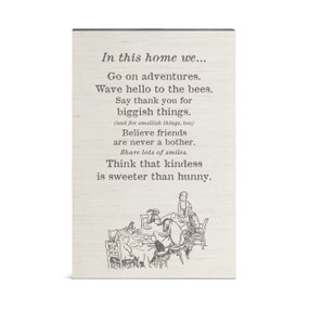 A wall art of Pooh and friends around a table and a saying about what we do "In this home..."