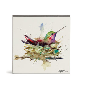 A small square watercolor wall art of a hummingbird in a nest.