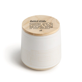 A white ceramic jar candle. The lid is wood with the saying "RE: Out of the Office Romantic getaway" with a short write up about someone on a romantic getaway.