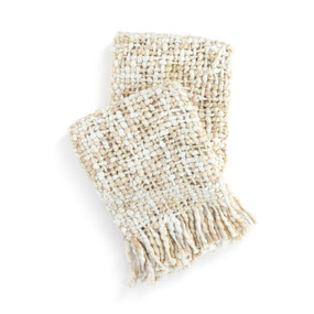 A loosely woven cream fringed blanket displayed folded over itself.
