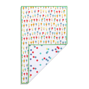 Top down view of a kitchen towel with a print of small and colorful ice cream cones on a white background on the front. The bottom right corner is folded up to show the back of the towel, which has a print of green, red, blue and yellow polka dots on a white background.