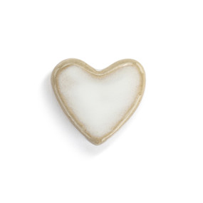 Top down view of a small white heart shaped ceramic token.