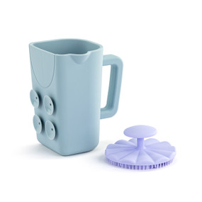 Front view of a blue bath cup and purple brush set. The cup is turned so the handle is on the right and suction cups are to the left. The brush is sitting to the right of the cup, bristle side down.